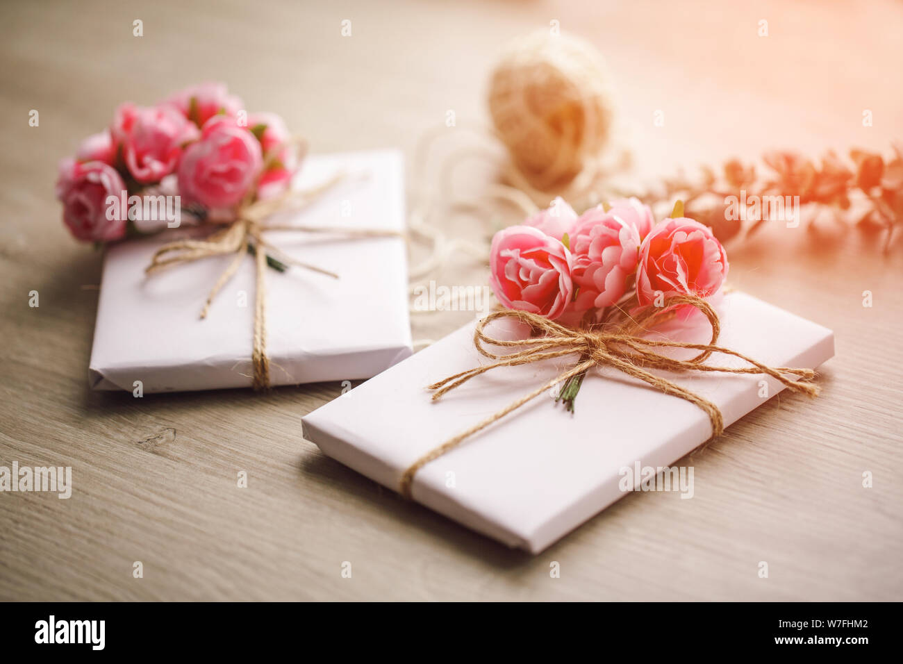 Boîte de cadeau faite à la main enveloppée de papier avec branche de roses. Branche d'eucalyptus et bobines rustiques de corde de chanvre sur fond Banque D'Images