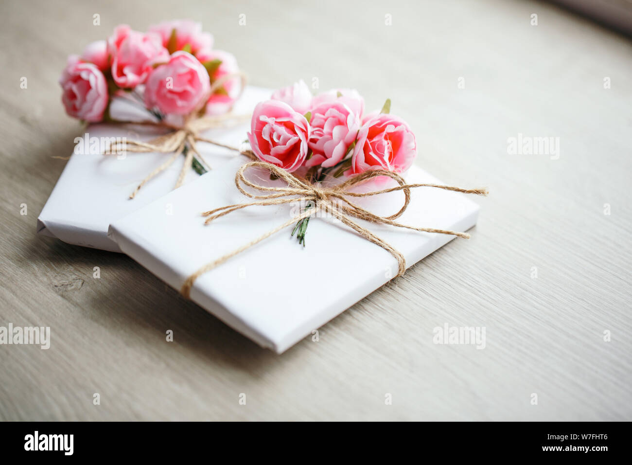 Quelques boîtes cadeau enveloppées de papier blanc artisanal simple et décorées avec un bouquet de roses et un bouquet d'eucalyptus. Banque D'Images