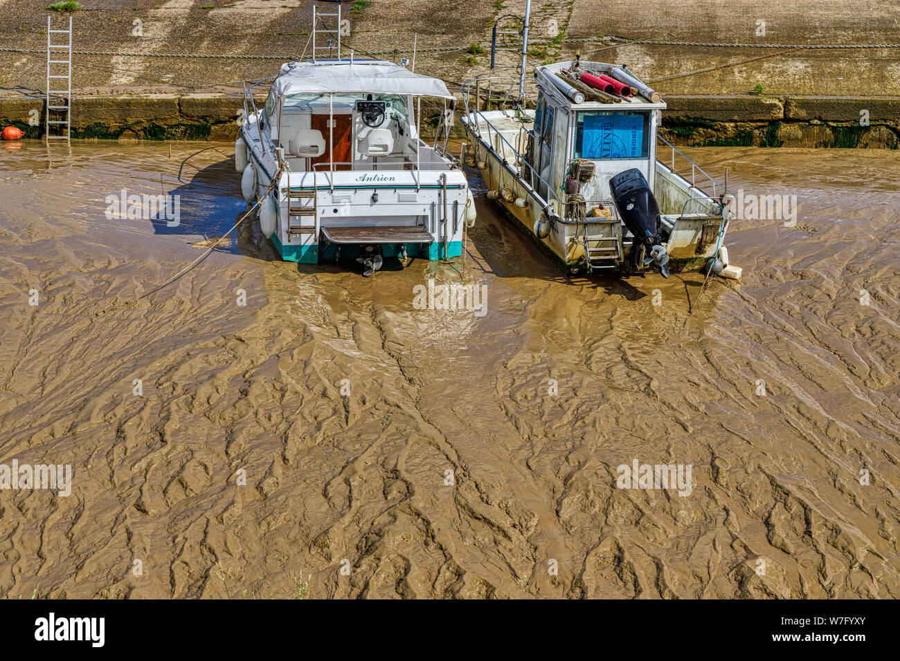 Deux petits bateaux se sont installés sur les terrains boueux de l'estuaire de la Saugeron à marée basse dans la région de Blaye, près de Bordeaux, dans le département du Nord de la France. Banque D'Images