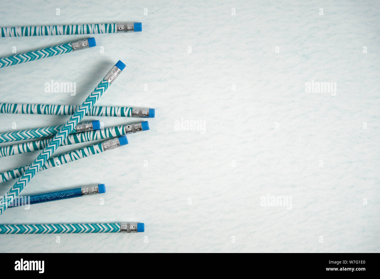 Concept retour à l'école avec des crayons blanc et bleu sur un fond bleu sarcelle marbrée Banque D'Images