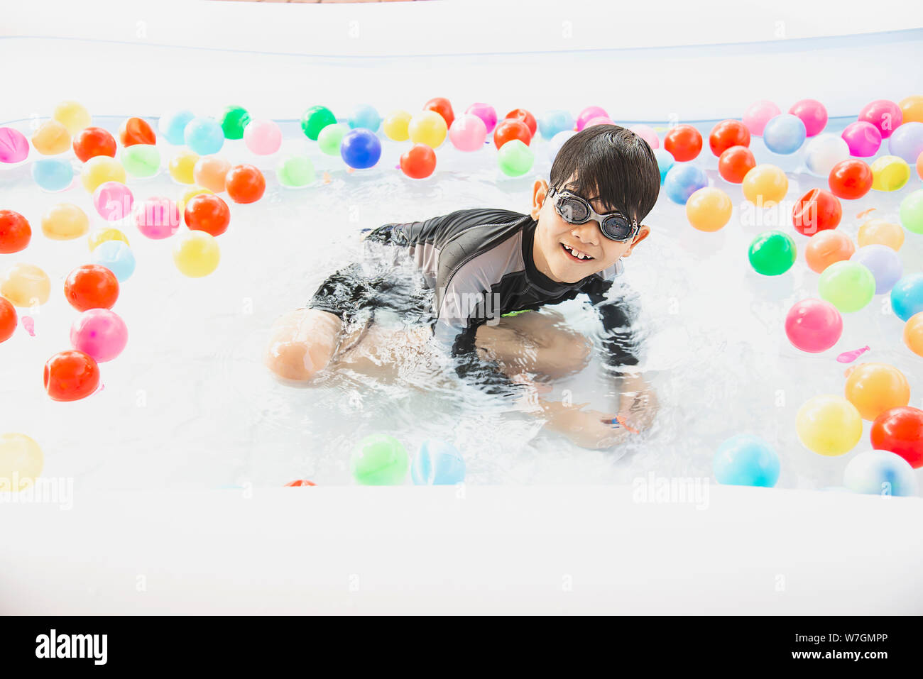 Garçon jouant avec boule colorée en petite piscine toy - happy boy dans l'eau piscine concept jouet Banque D'Images