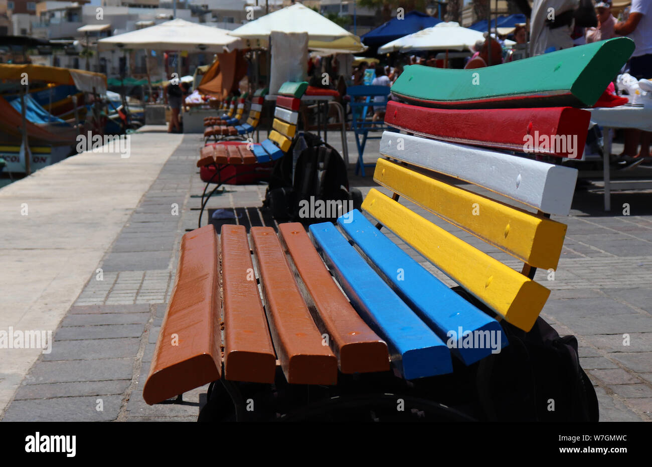 Des bancs peints en couleurs traditionnelle maltaise sur le quai à Marsaxlokk, Malte Banque D'Images