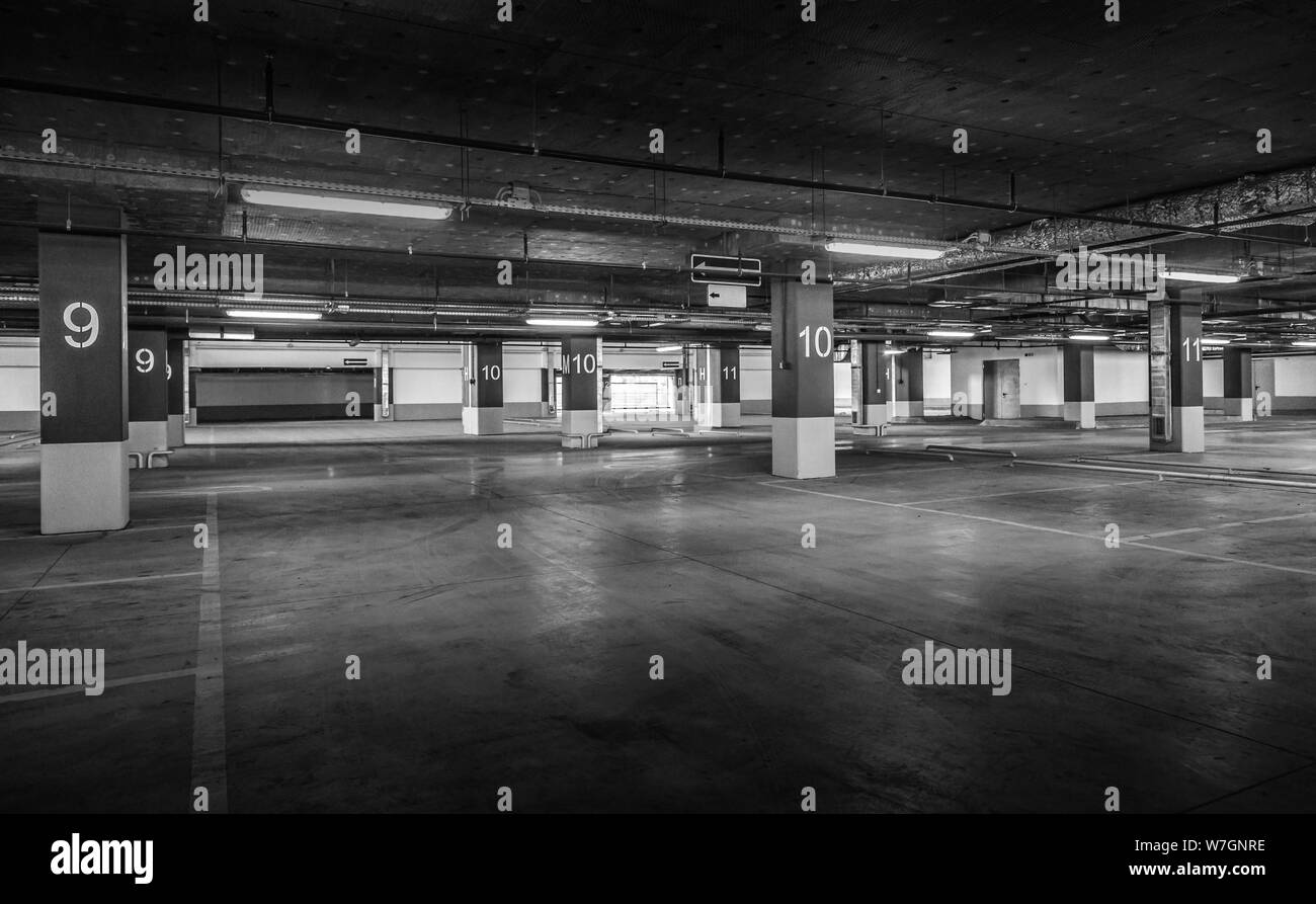 Grungy, faiblement éclairées garage parking vide avec éclairage vertical et un panneau de sortie qui pendent du plafond. Banque D'Images