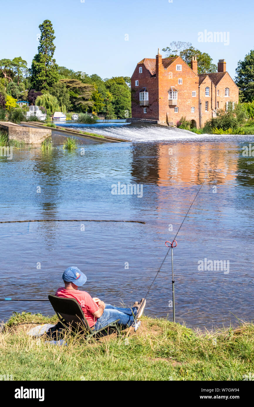 Soleil matinal sur Cropthorne Mill et un pêcheur au bord de la rivière Avon à Fladbury Worcestershire, Royaume-Uni Banque D'Images