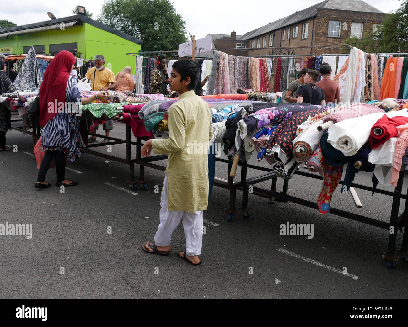 Les acheteurs asiatiques à la recherche de rouleaux de tissus et matériaux alors que des magasins Bolton marché plein air en Angleterre. photo DON TONGE Banque D'Images