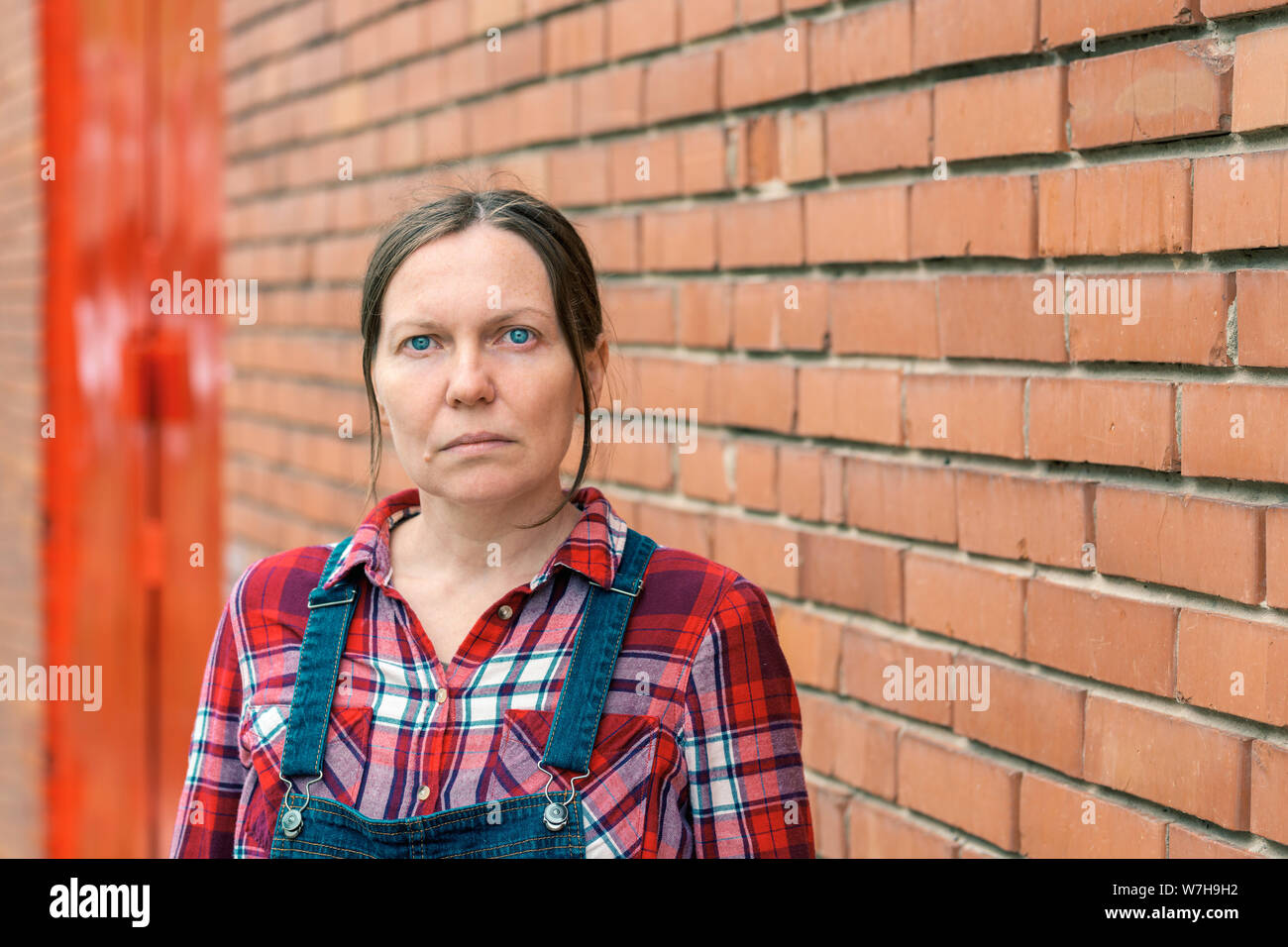 Portrait de la productrice à la ferme, cropped portrait de femme en chemise  à carreaux et jeans salopettes salopette avec bretelles looking at camera  while standi Photo Stock - Alamy