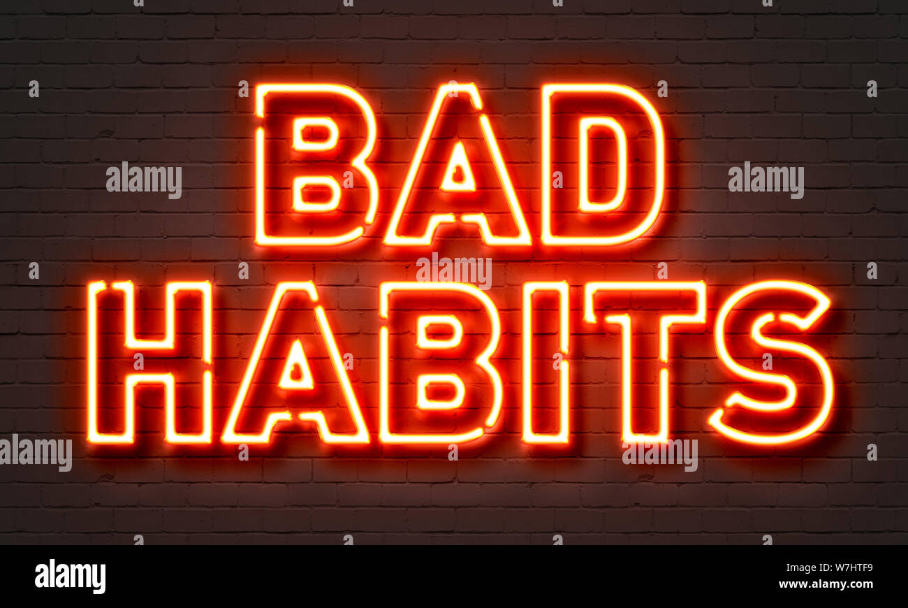 Mauvaises habitudes neon sign on brick wall background Banque D'Images