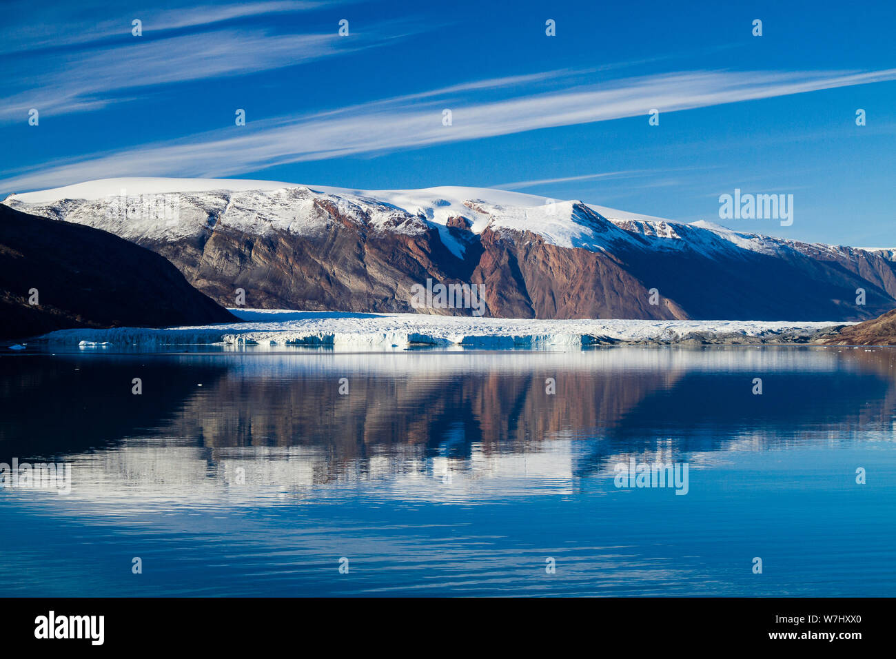 Un vaste glacier dérivant lentement dans l'eau du fjord est vu de cinq kilomètres de là, dans l'est du Groenland (cette photo est à 40mm, par rapport à la précédente à 18mm, d'où la différence d'échelle) Banque D'Images