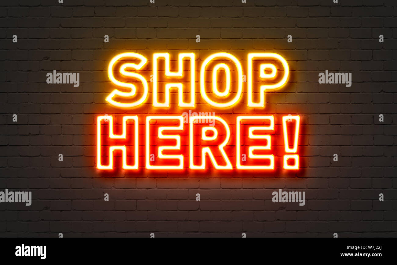 Shop ici neon sign on brick wall background Banque D'Images