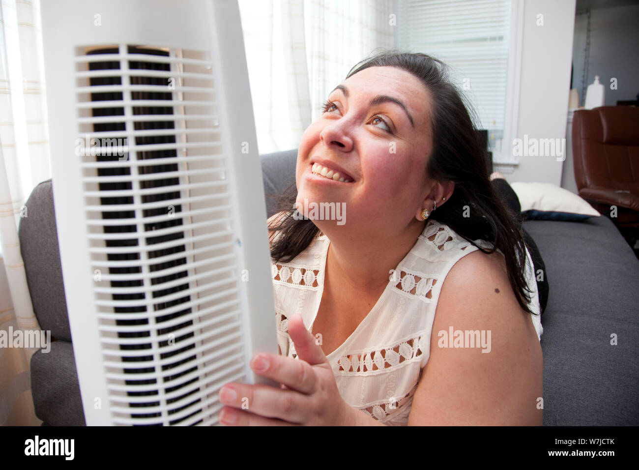 Une femme qui est chaud dans la chaleur des étreintes et regarde affectueusement son air fan Banque D'Images