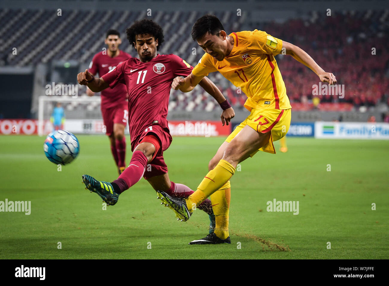 Li Xuepeng, droite, de Chine, de défis Akram Afif du Qatar dans leur groupe un Round 10 match pendant la Coupe du Monde FIFA 2018 Qualificatif la Russie à Doha, Q Banque D'Images