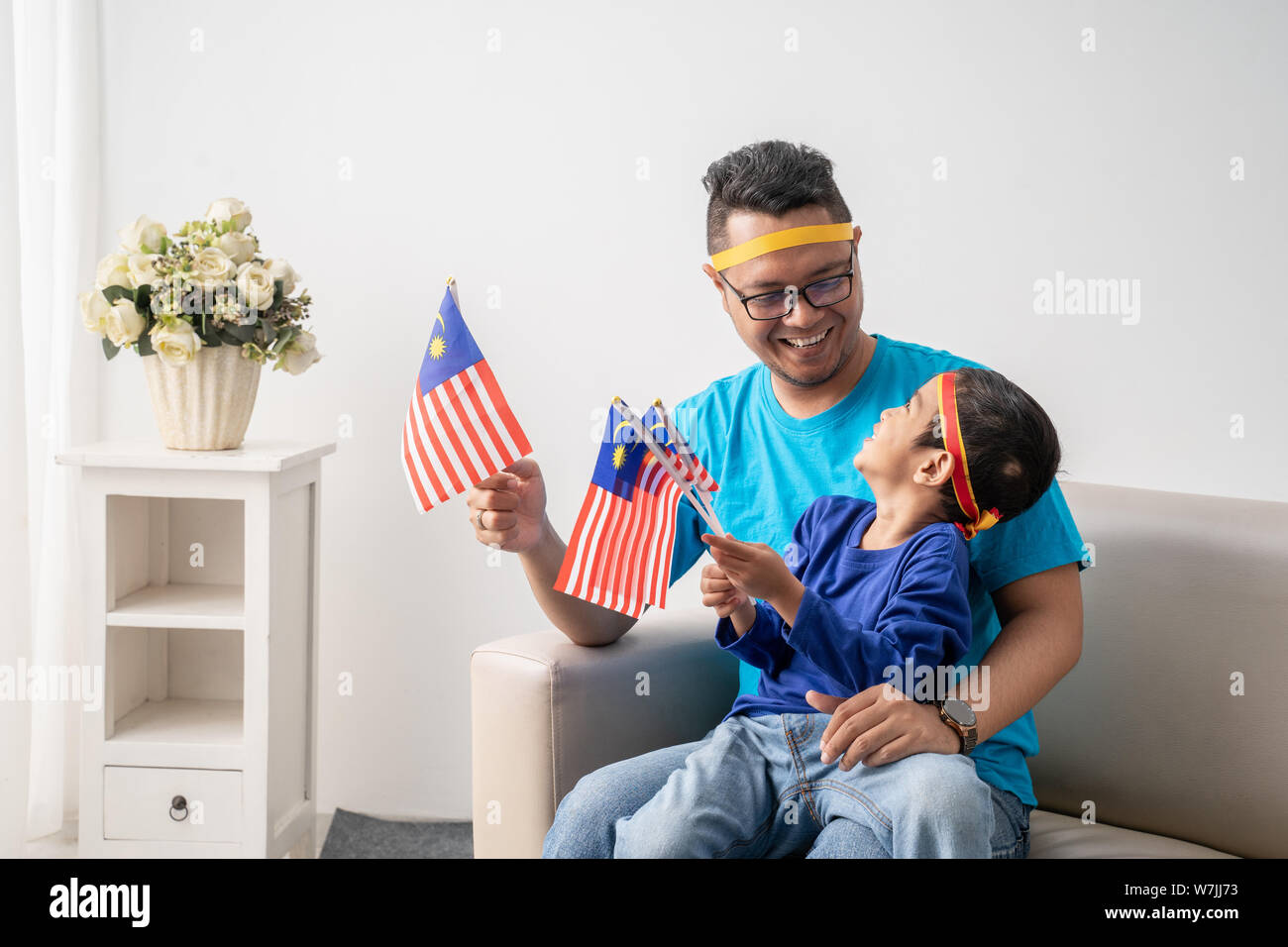 Père et fils tenant un drapeau malaisien ensemble tout en regardant des match de foot Banque D'Images