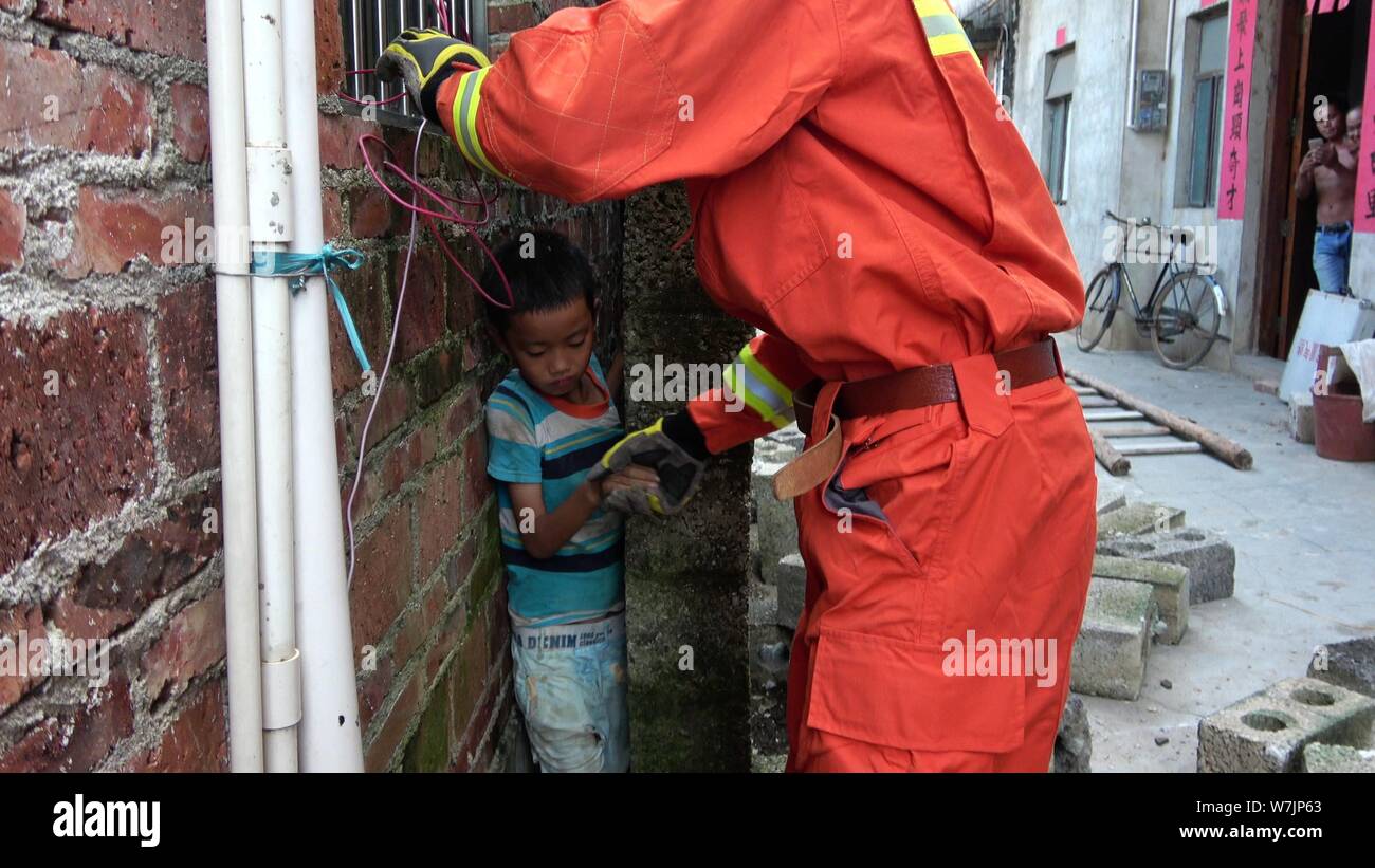 Un pompier chinois tente de sauver les neuf ans, garçon surnommé chinois Huang se bloquent dans un espace de 20 centimètres entre les murs Banque D'Images