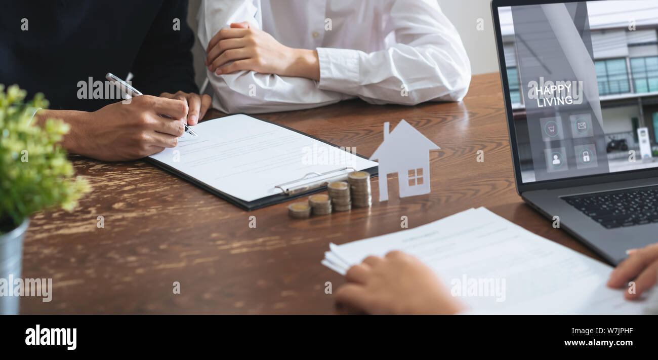 Des couples ont signé un contrat pour acheter une maison par le courtier. Coin d'empiler de l'argent et le modèle chambre placé sur la table, la croissance de l'activité financière. Banque D'Images