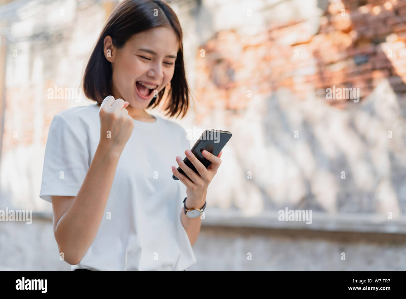 Femme de happy smiling and holding smart phone avec surpris du succès.L'idée d'utiliser le téléphone est essentiel dans la vie quotidienne. Banque D'Images