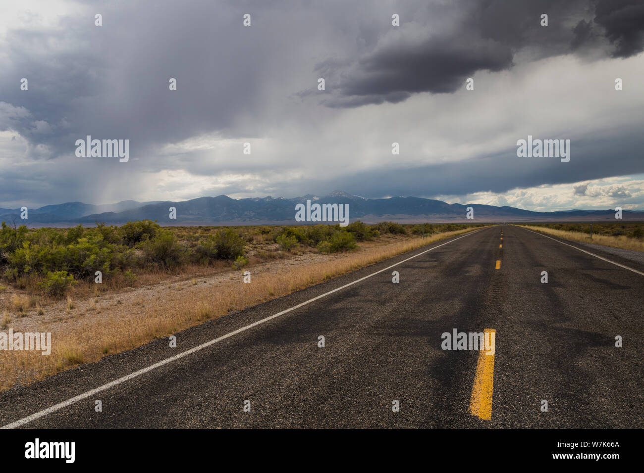 Les lignes jaunes d'une autoroute à deux voies, l'US Highway 50, sous un ciel couvert au milieu du haut désert à la frontière de l'Utah Nevada sur un recul d'été Banque D'Images