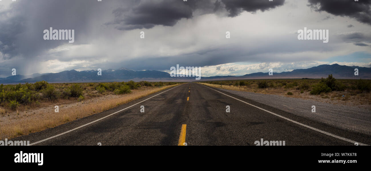 Les lignes jaunes d'une autoroute à deux voies, l'US Highway 50, sous un ciel couvert au milieu du haut désert à la frontière de l'Utah Nevada sur un recul d'été Banque D'Images