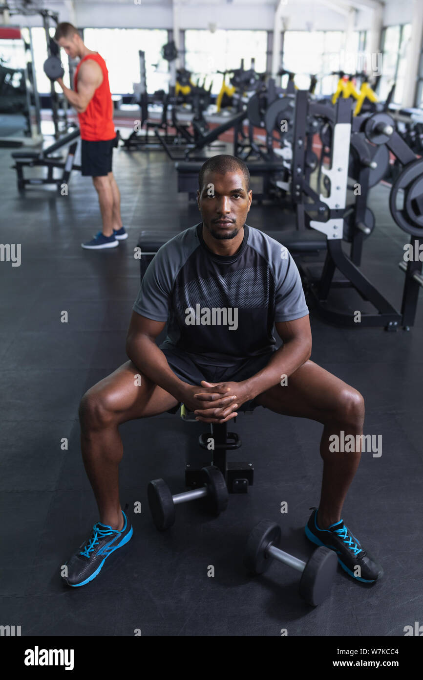 Homme en vous relaxant avec les mains jointes sur l'établi dans le centre de remise en forme Banque D'Images