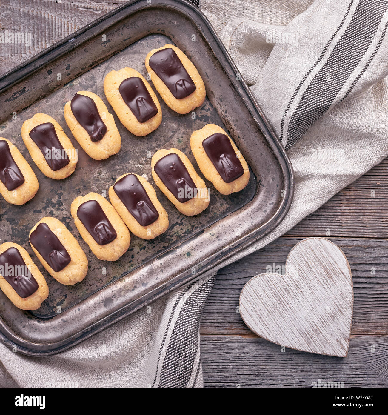 Mini éclairs vanille glaçage au chocolat sur le plateau métallique, vue du dessus sur la composition de la place,rustique en bois Banque D'Images