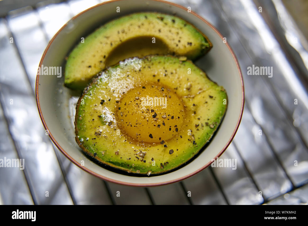 Oeufs crus 12.2005 dans un split avocat prêt à être cuit avec du sel et du poivre pour un déjeuner nutritif. Banque D'Images