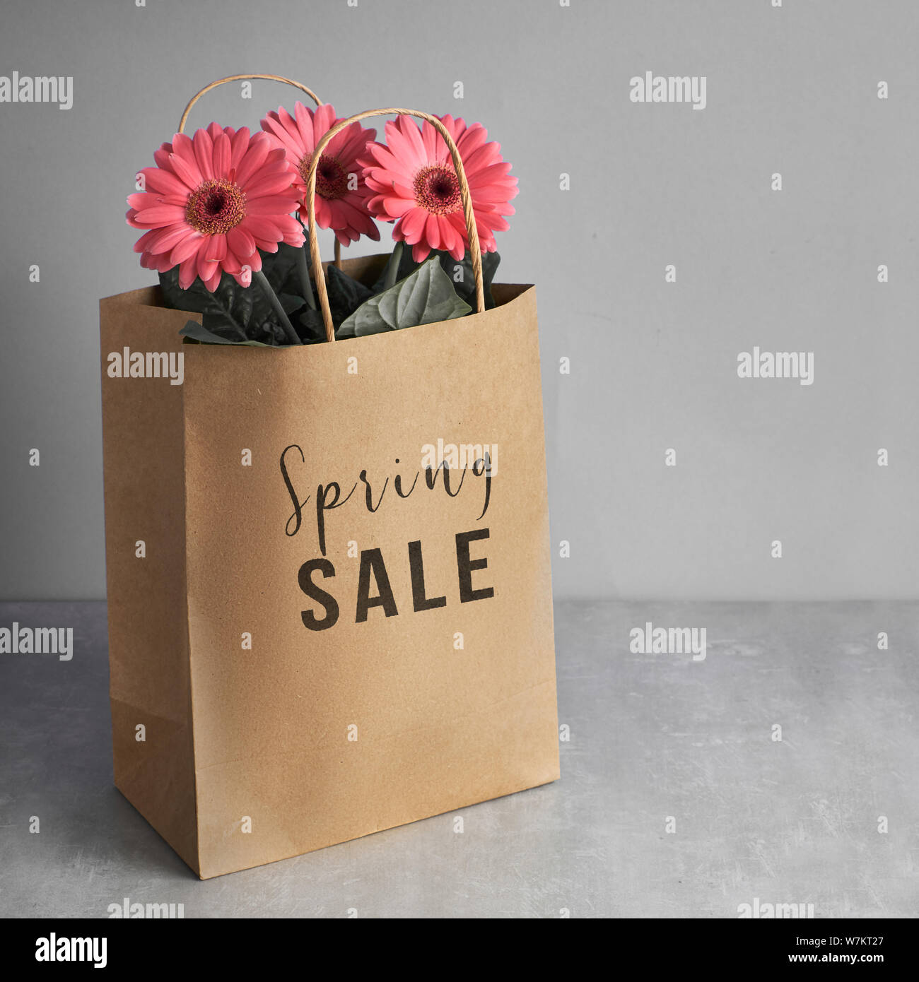 Gerbera fleurs corail daisy et d'artisanat sacs papper sur fond de papier vert, carré, la composition de l'image concept vente de printemps avec texte 'Spr Banque D'Images