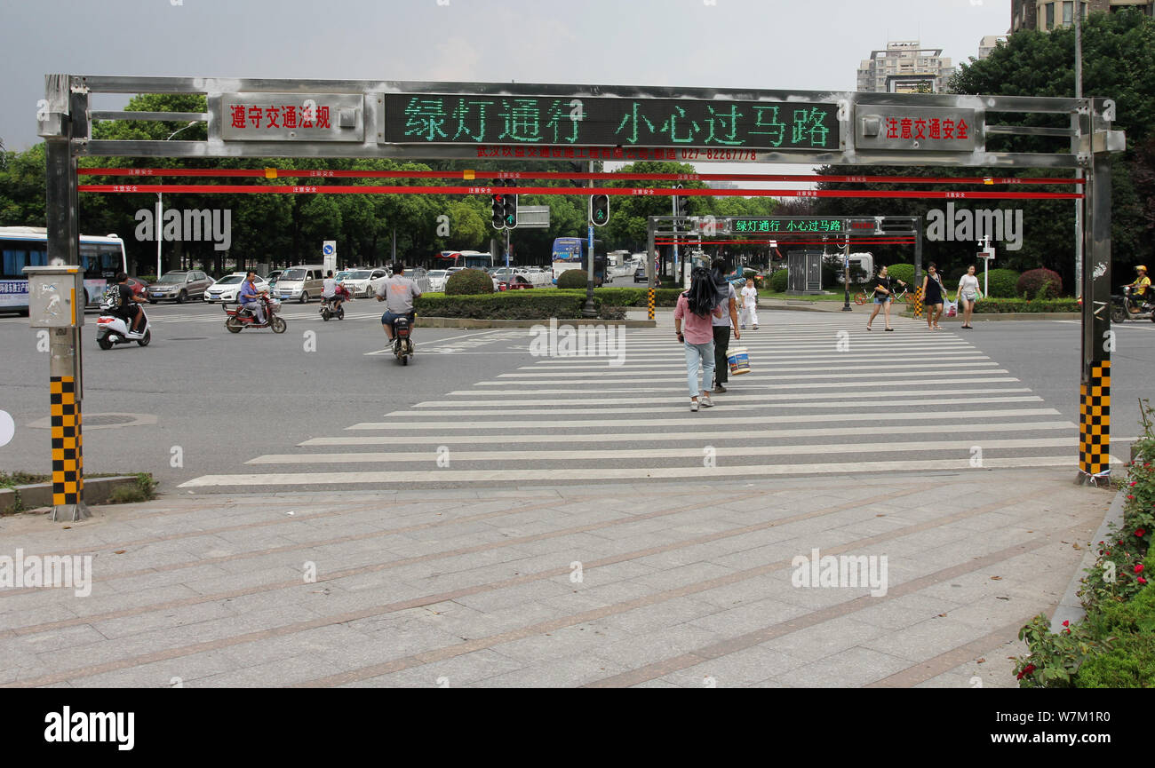 Les piétons traverser la route comme le système de corde automatique s'ouvre à un passage à niveau de la rue dans la ville de Wuhan, province du Hubei en Chine centrale, 25 août 2017 Banque D'Images