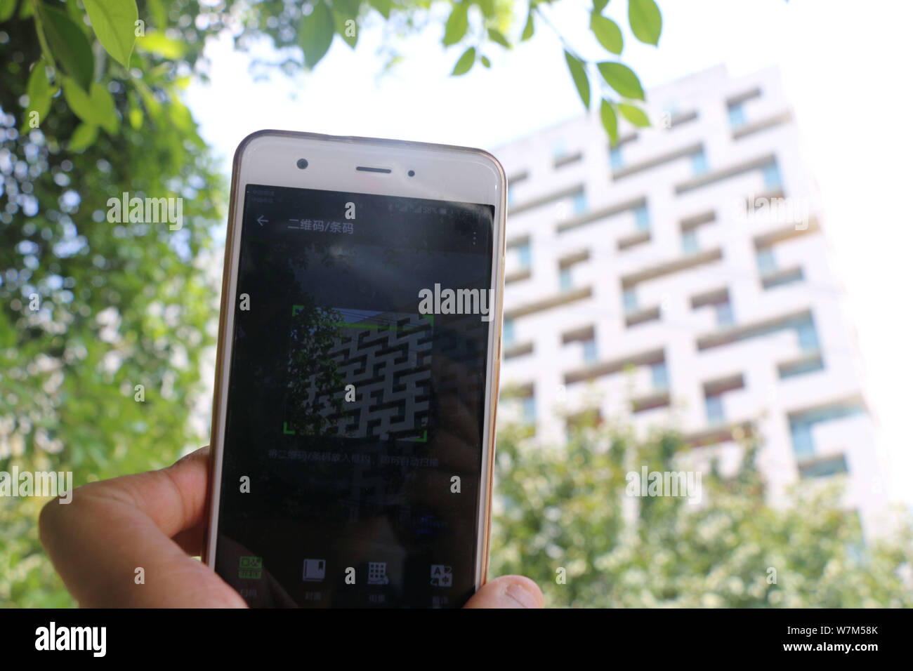 Un piéton utilise son smartphone pour scanner le bâtiment résidentiel comprenant la forme de QR Code sur sa surface à Chongqing, Chine, 16 août 2017. Banque D'Images