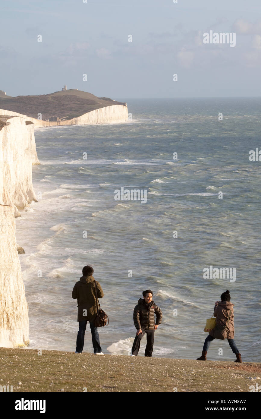 Les gens à prendre des photos en face de sept Sœurs des falaises de craie avec une mer agitée. South Downs, Angleterre, novembre 2011. Banque D'Images