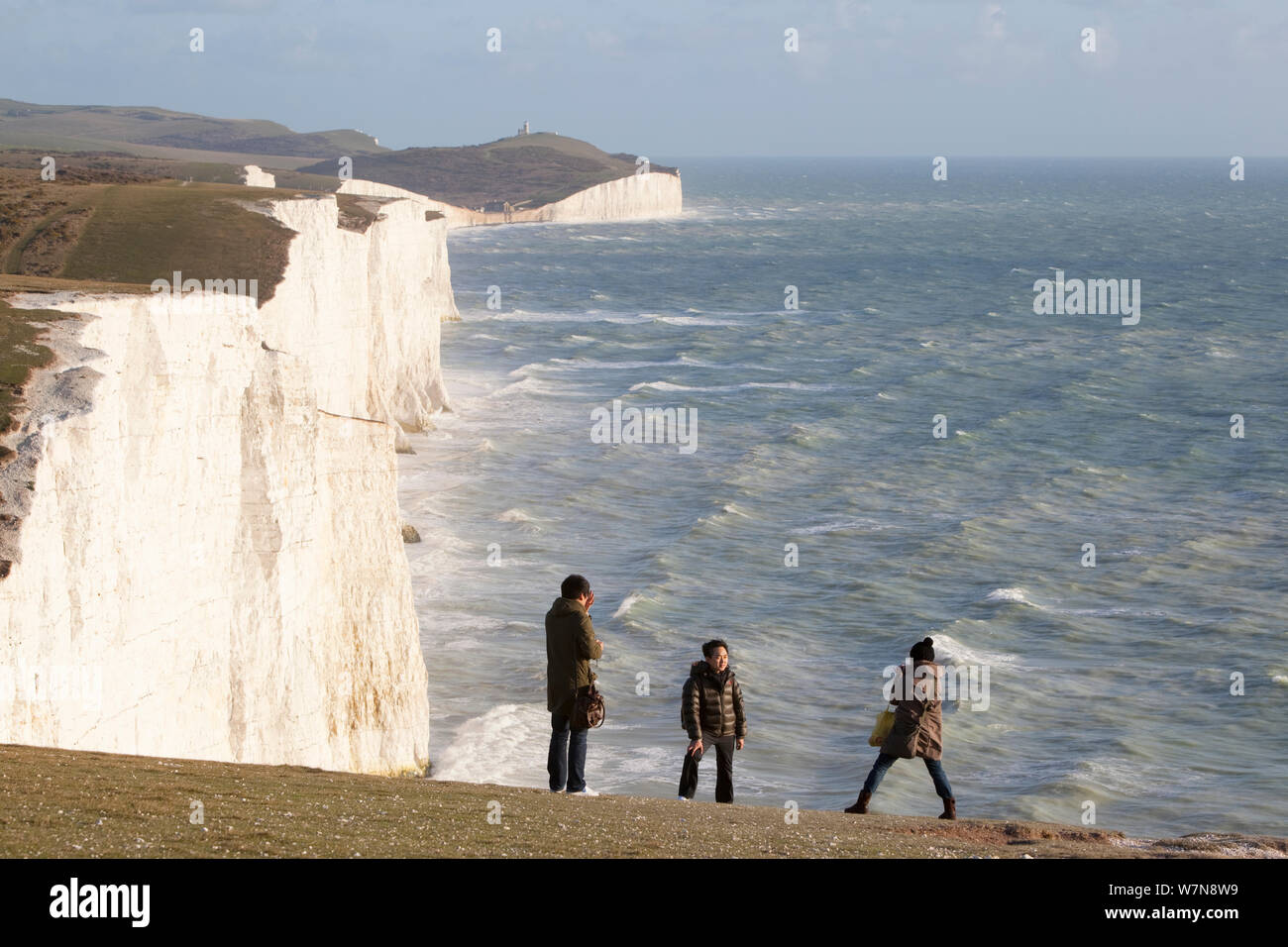 Les gens à prendre des photos en face de sept Sœurs des falaises de craie avec une mer agitée. South Downs, Angleterre, novembre 2011. Banque D'Images