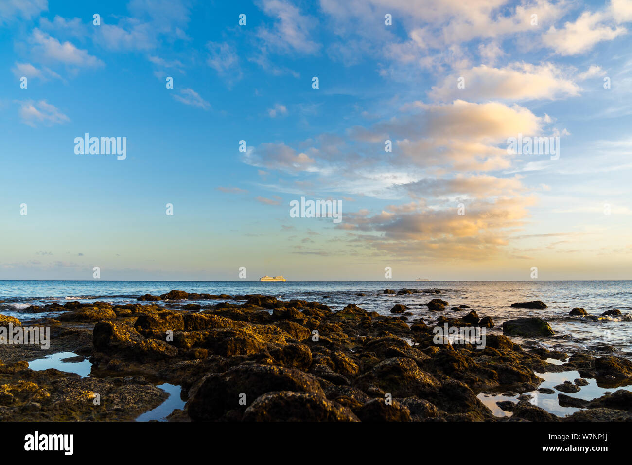 L'Espagne, Lanzarote, coucher de soleil ciel nuages colorés au cours des interminables de l'eau de l'océan Atlantique à Stony coast Banque D'Images