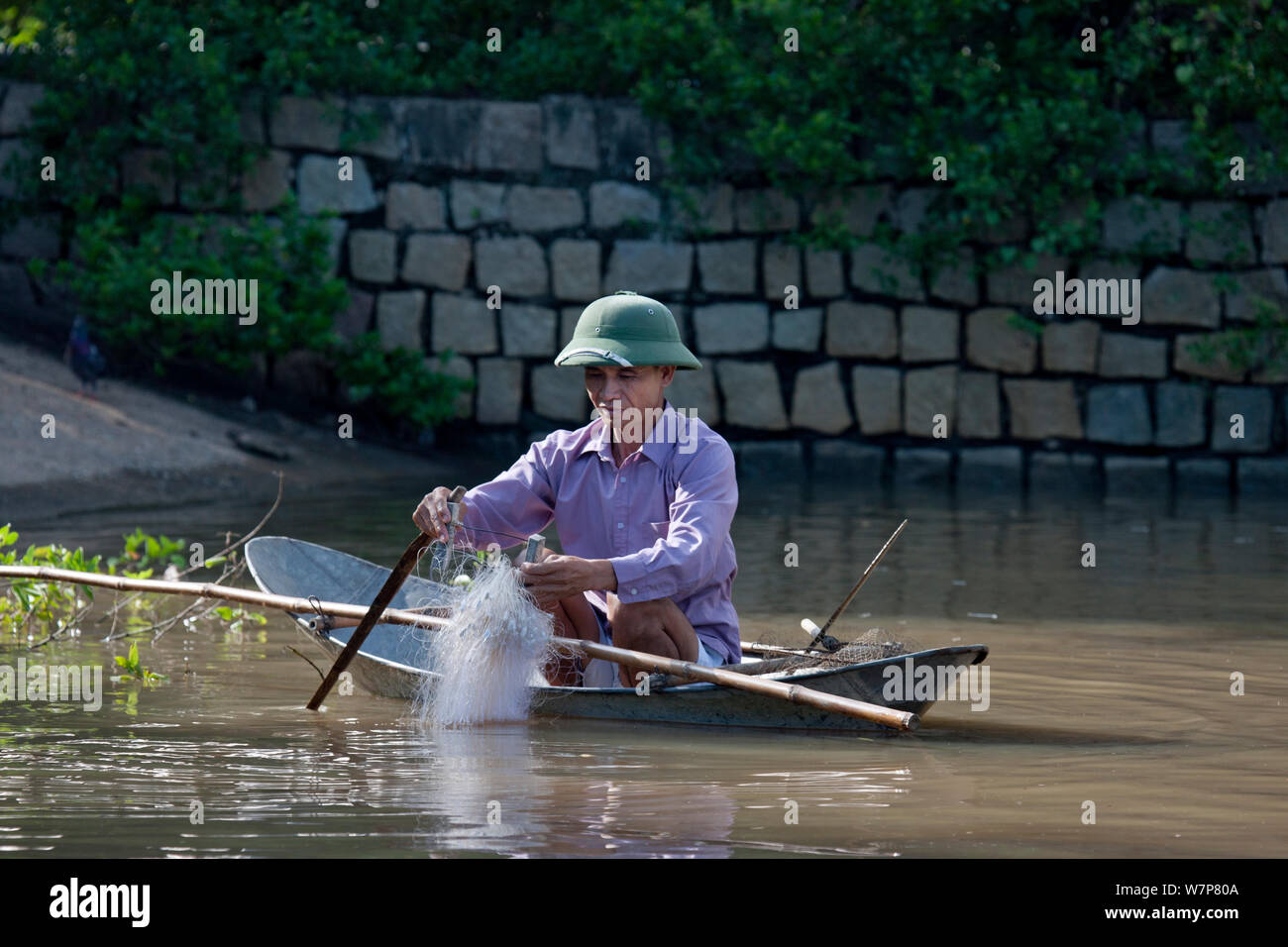 L'homme dans le petit bateau de pêche avec filet, Phan Thiet, Vietnam. Banque D'Images