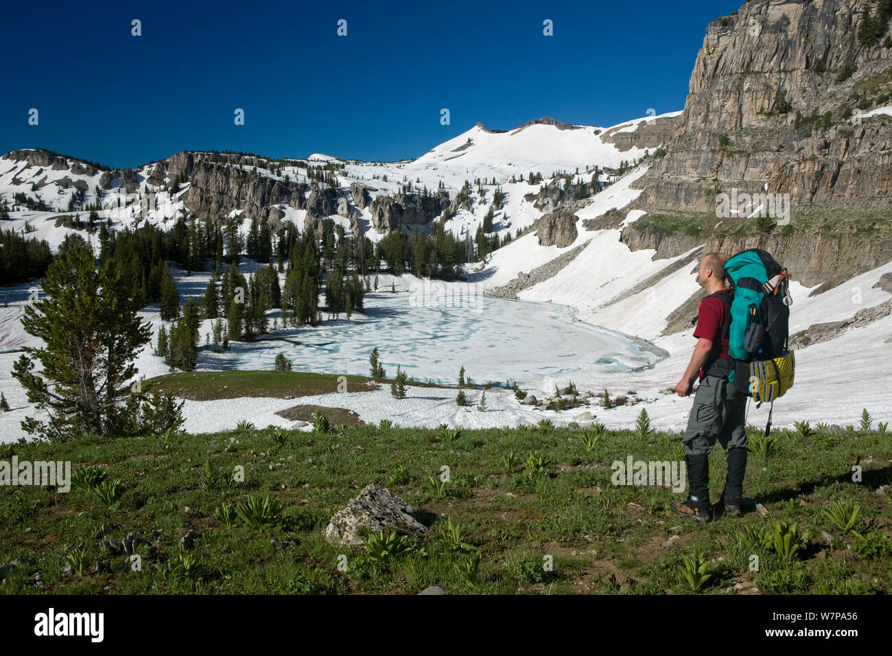 Backpacker au-dessus du lac Marion congelé le long de la Teton Crest Trail dans le Grand Teton Natoinal Park. Wyoming, USA, juillet 2011 Parution du modèle Banque D'Images