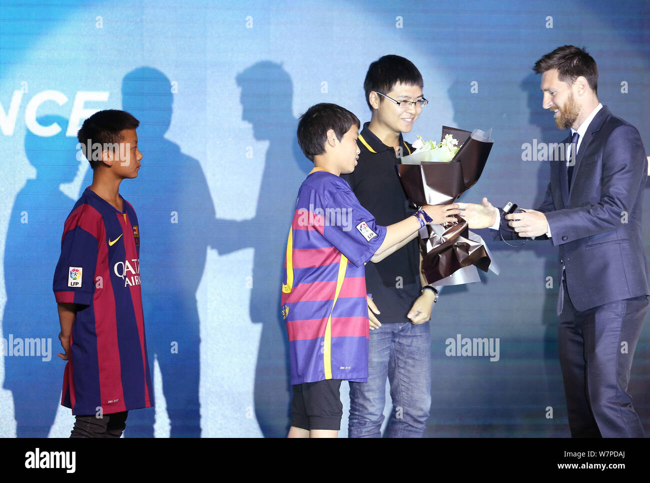 L'attaquant argentin Lionel Messi du FC Barcelone, à droite, reçoit des fleurs d'un jeune fan chinois au cours d'une conférence de presse pour l'expérience Messi Banque D'Images