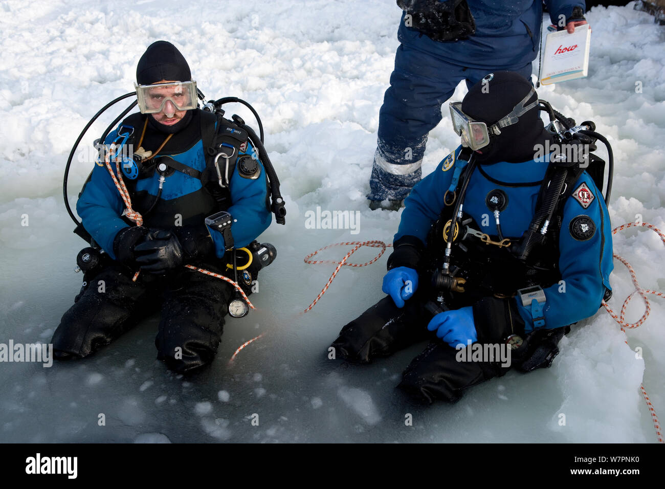 Couple de plongeurs à l'entrée triangulaire scié maina (trou) avec glace fondue prêt à faire de la plongée sous les glaces du cercle arctique, centre de plongée, mer Blanche, la Carélie, dans le Nord de la Russie, Mars 2010 Banque D'Images