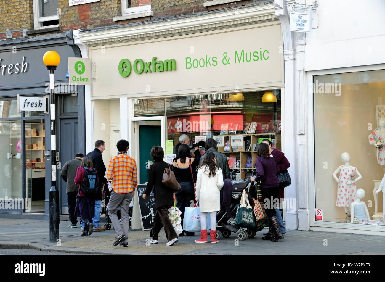 Les personnes à la recherche dans la fenêtre d'un magasin de charité Oxfam Marylebone High Street, London Borough de Westminster, en Angleterre, Royaume-Uni, mars 2009 Banque D'Images