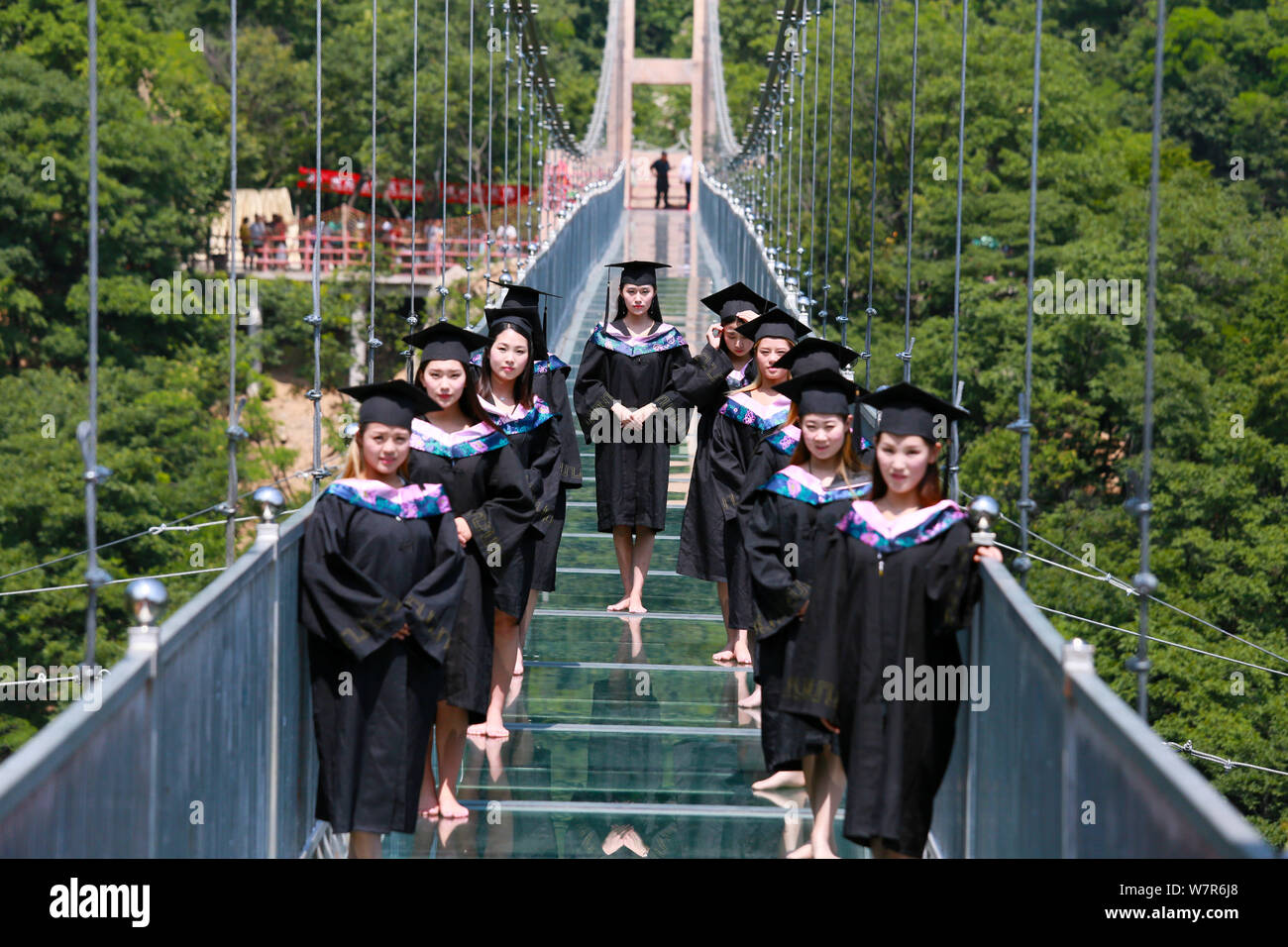 Les femmes vêtus de toges universitaires posent pour l'obtention du diplôme de photos sur le pont en verre à l'Tianlongchi dans la zone panoramique de la ville de Pingdingshan, central Banque D'Images