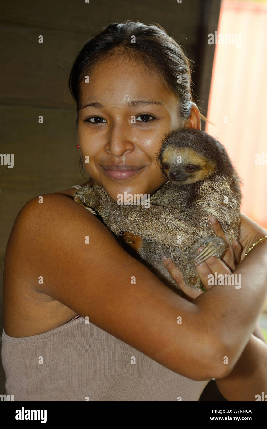 Young Girl holding à gorge pâle sloth / Aï (Bradypus tridactylus) Guyane française. Banque D'Images