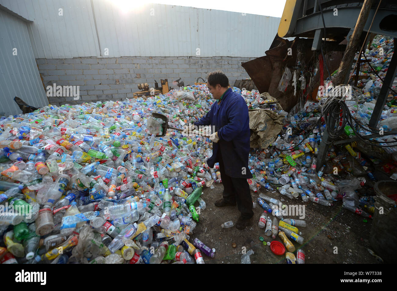Un travailleur chinois efface les bouteilles en plastique à la bouteille en plastique de recyclage, qui piège un homme, dans la ville de Ji'nan, l'est la province de Shandong, Chine Banque D'Images