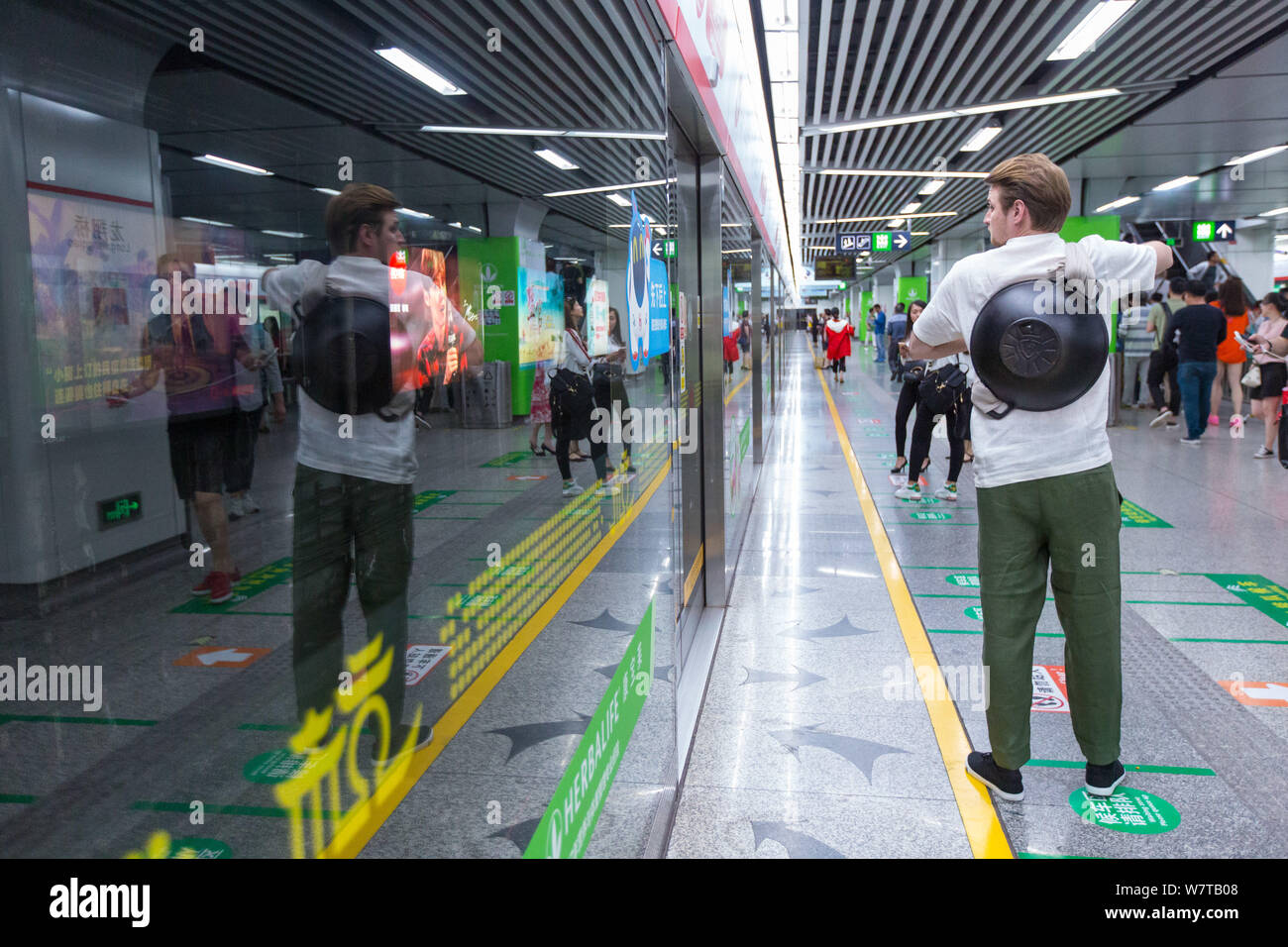 L'homme russe Dmitri, vêtu de vêtements traditionnels chinois et de transporter un pot fixé à son dos, attend une rame de métro à une station de métro à Hangzh Banque D'Images