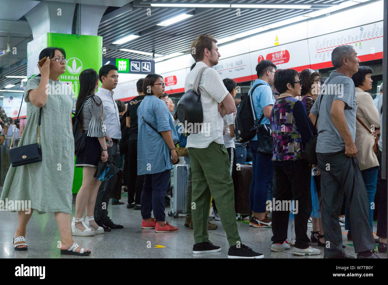 L'homme russe Dmitri, vêtu de vêtements traditionnels chinois et de transporter un pot fixé à son dos, attend une rame de métro à une station de métro à Hangzh Banque D'Images