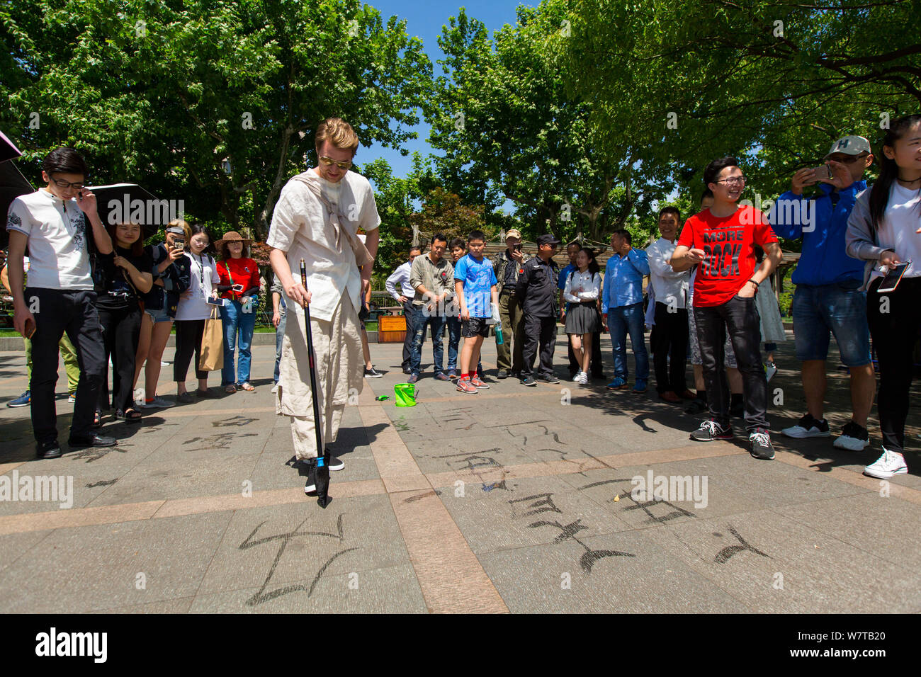 L'homme russe Dmitri, vêtu de vêtements traditionnels chinois et de transporter un pot fixé à son retour, écrit à la calligraphie chinoise West Lake scenic sp Banque D'Images