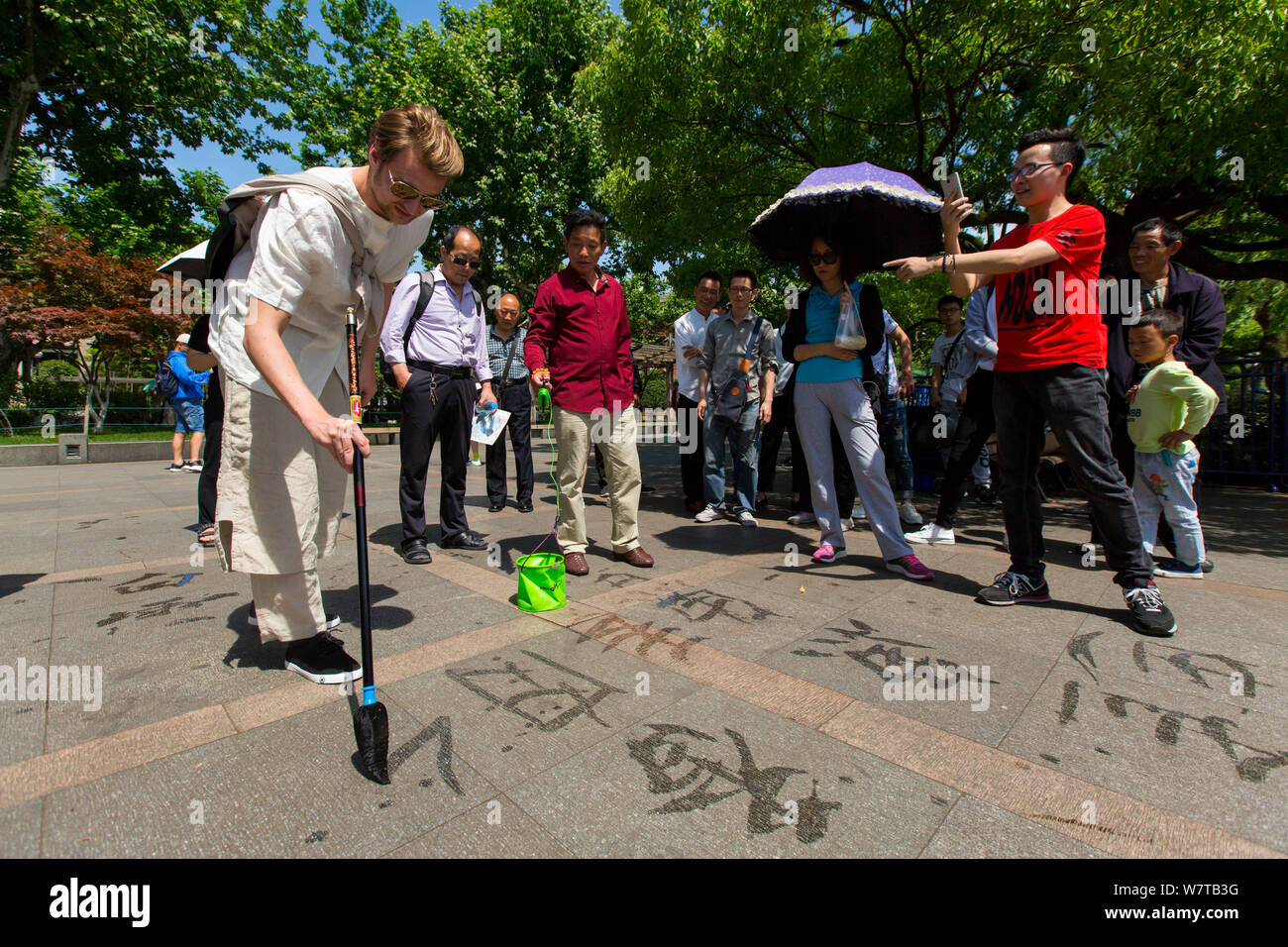 L'homme russe Dmitri, vêtu de vêtements traditionnels chinois et de transporter un pot fixé à son retour, écrit à la calligraphie chinoise West Lake scenic sp Banque D'Images