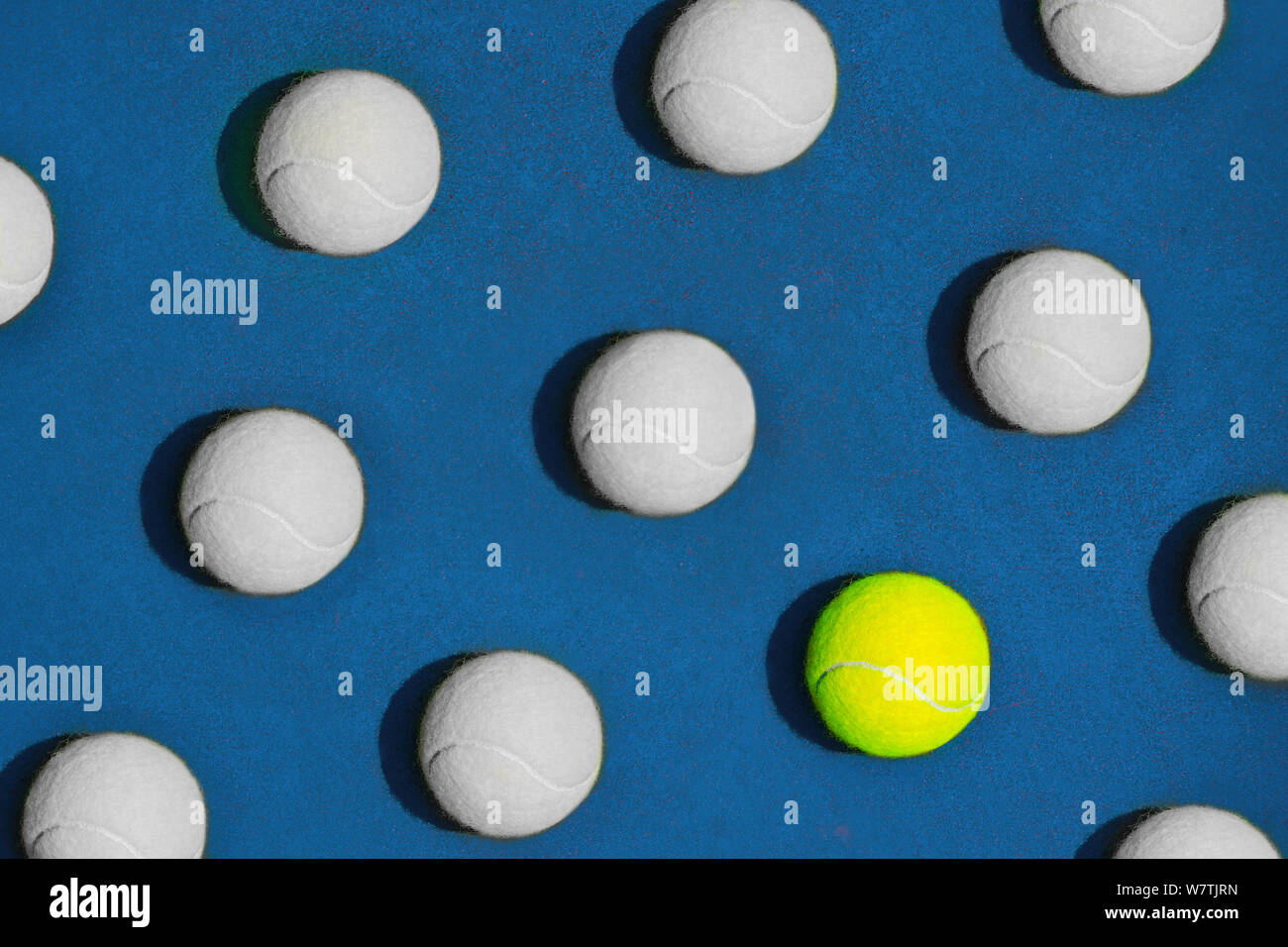 La composition créative faite avec balle de tennis jaune et boules blanches sur fond bleu. Tennis Sport tendance. La diversité et la différence concept. Mise à plat Banque D'Images