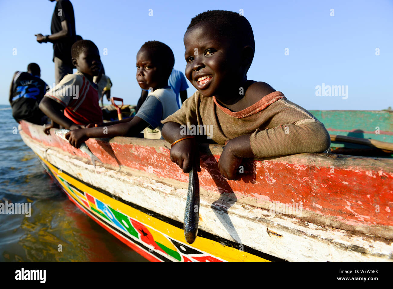 Enfants jouant avec des poissons sur un bateau de pêche, Eticoga, Orango Island, de la Guinée-Bissau, décembre 2013. Banque D'Images