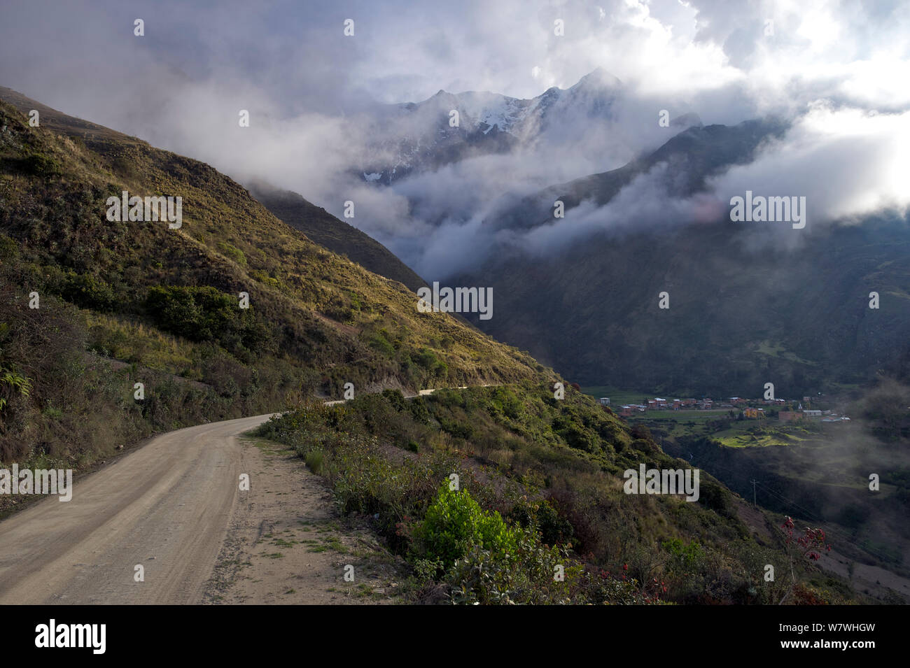 Route non revêtue avec le village de Totoral Montagne Illimani et partiellement masquée par les nuages au loin, la Bolivie, octobre 2013. Banque D'Images