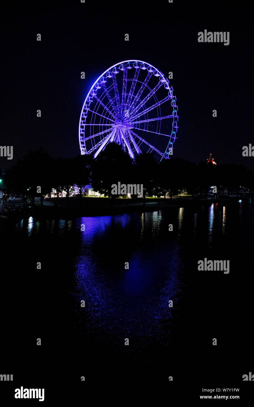 La roue d'observation La Grande Roue de Montréal, Québec, Canada la nuit, éclairé par une lumière bleue et se reflètent dans le lac. Banque D'Images