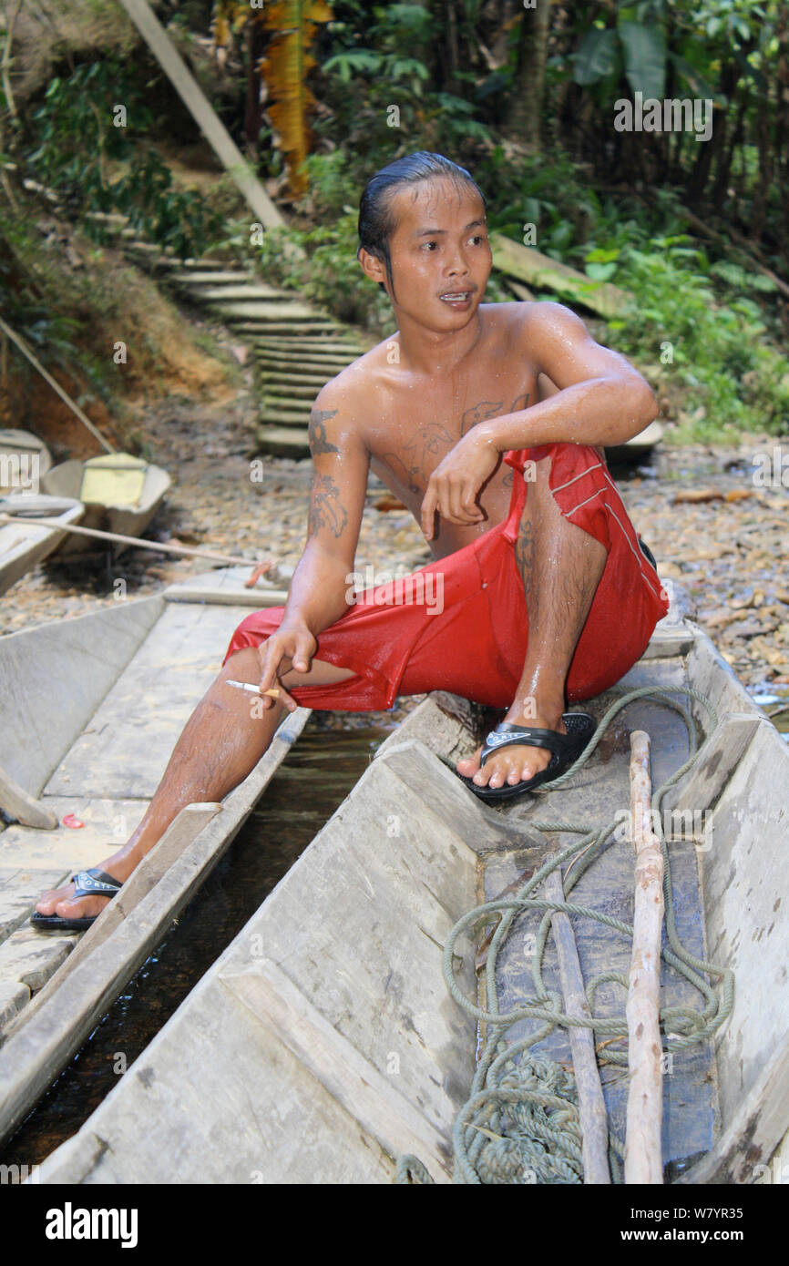 Garçon Dayak fumeurs en canoë, l'ouest de Kalimantan, la partie indonésienne de Bornéo. Juin 2010. Banque D'Images