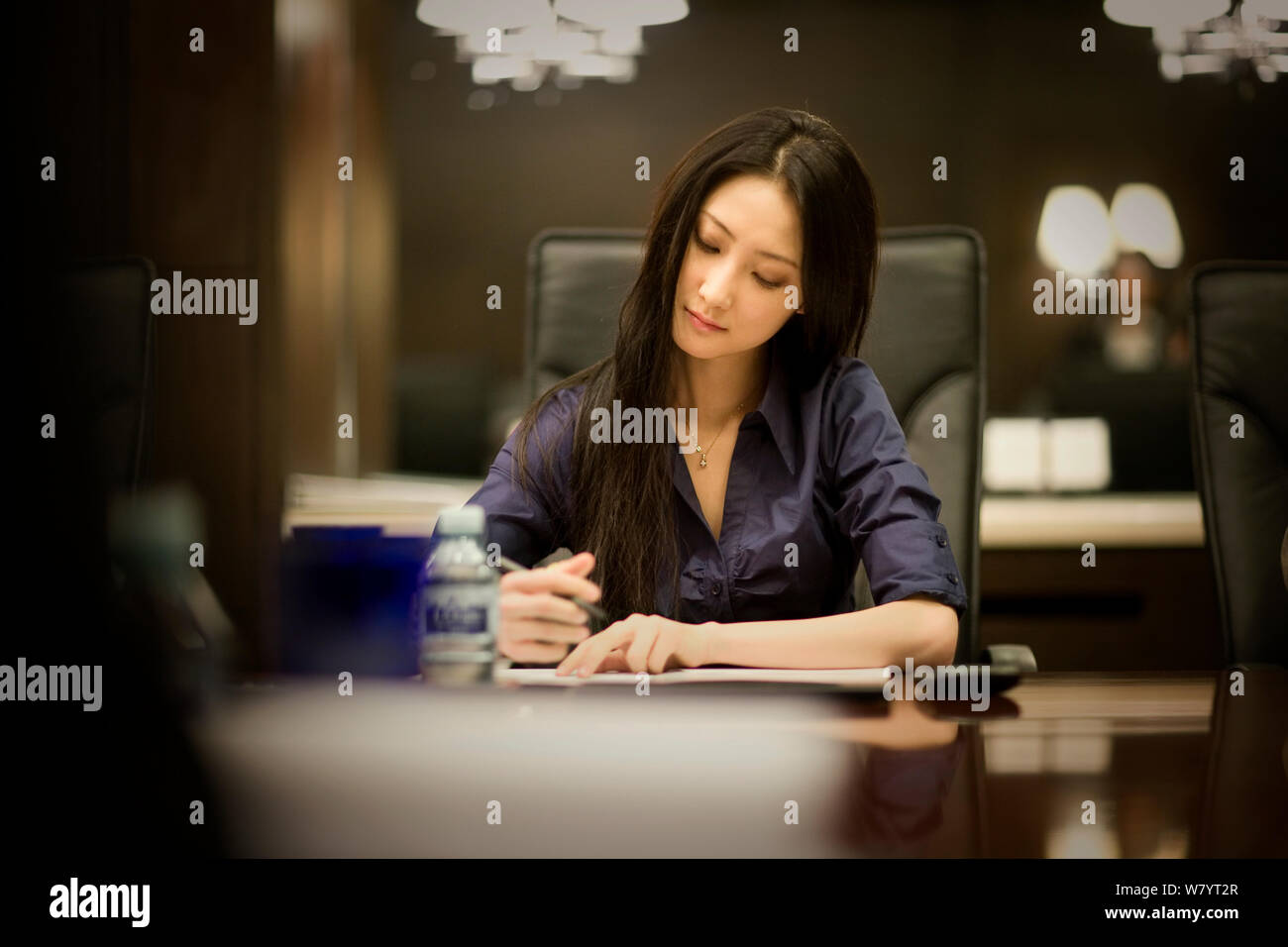 Jeune adulte femme d'affaires en prenant des notes dans une salle de réunion. Banque D'Images