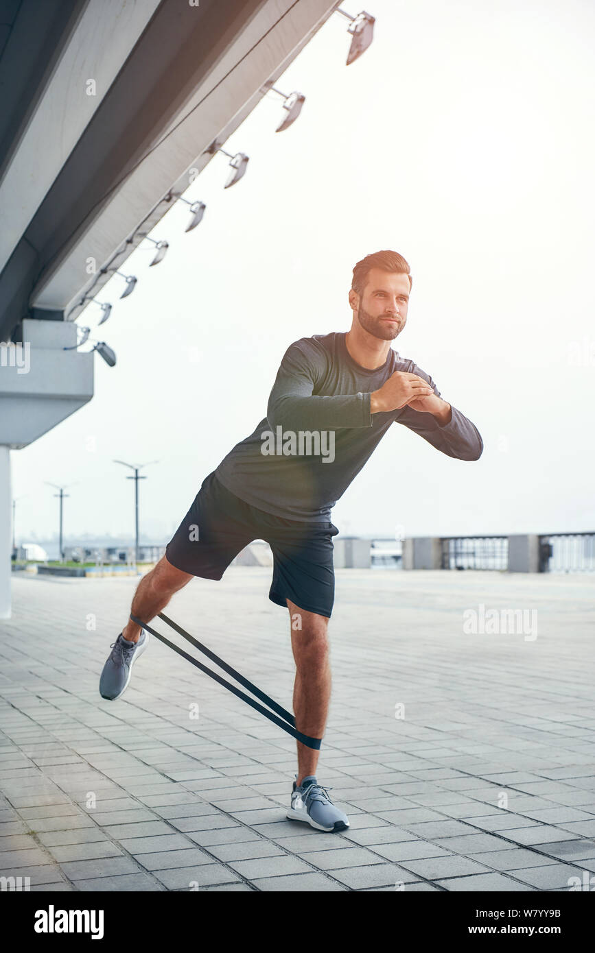 Vous pouvez faire plus de plein-longueur de jeune et confiant barbu homme dans les vêtements de sport faisant des exercices en se tenant debout à l'extérieur. Concept sport. Un mode de vie sain et actif Banque D'Images