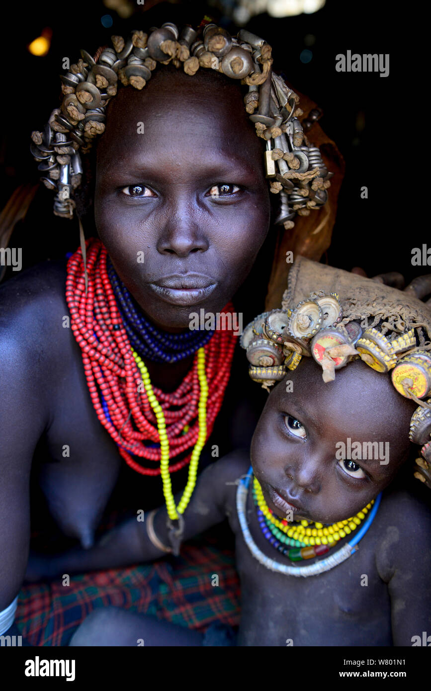Dassanech femme avec coiffe de plumes d'écrous et boulons, son fils avec coiffe de bouteilles. Tribu Dassanech, vallée de l'Omo. L'Éthiopie, Novembre 2014 Banque D'Images